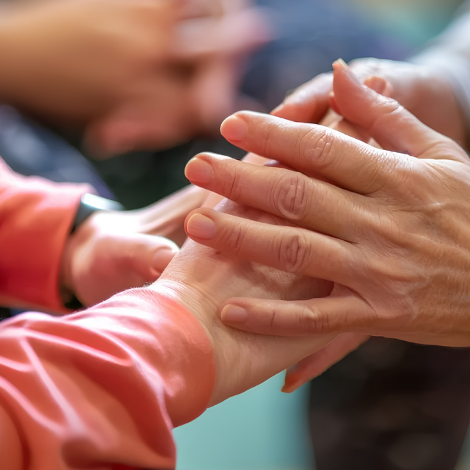 A diverse group of individuals standing in a circle, holding hands, symbolizing unity and support in aged care.