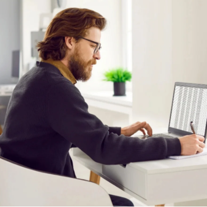 A man sits at a desk, focused on his laptop while learning Excel for beginners.